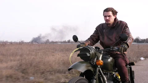 Side view of a stylish cool man in leather jacket driving vintage motorcycle Stock Footage 152982074