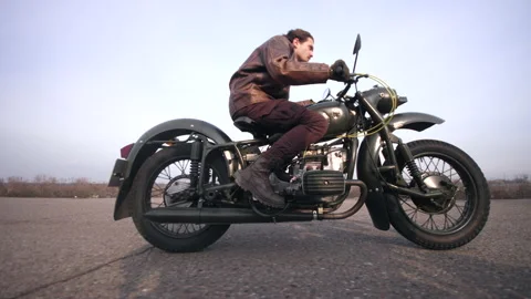 Side view of a stylish cool man in leather jacket driving vintage motorcycle Stock Footage 152983400