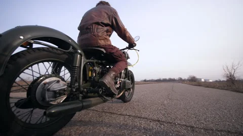 Side view of a stylish cool man in leather jacket driving vintage motorcycle Stock Footage 152983498