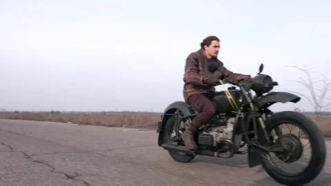 Side view of a stylish cool man in leather jacket driving vintage motorcycle Stock Footage 231970724
