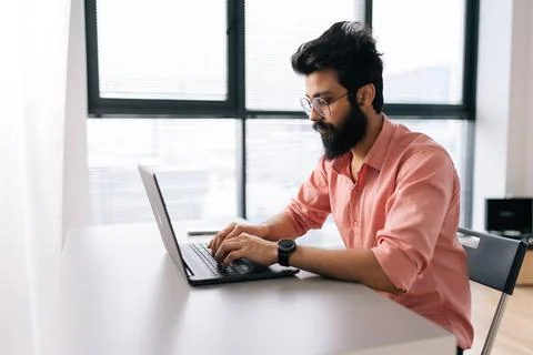 Side view of successful Indian programmer male in casual clothes working on Stockfoto's