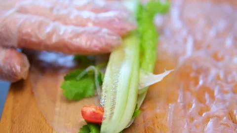 Side view of a sushi chef hands leveling triangle Japanese roll in rice paper Stock Footage 302082229