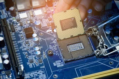 Side view of technician assembling CPU on motherboard. Stock Photos
