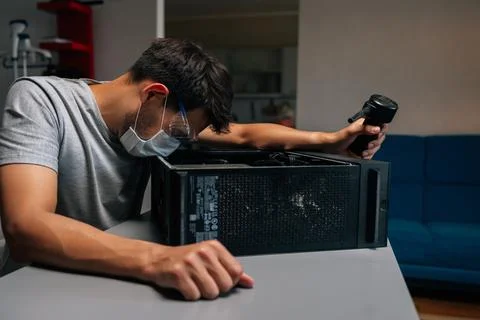 Side view of technician in face mask and safety glasses cleaning computer case Stock Photos