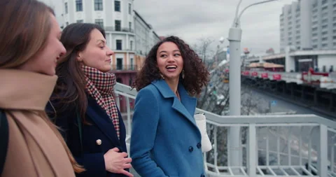 Side view three happy young multiethnic female friends walking along city bridge Stock Footage 152496833