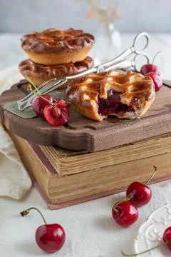 Side view of three individual cherry pies on a wooden board on top of a stack 写真素材