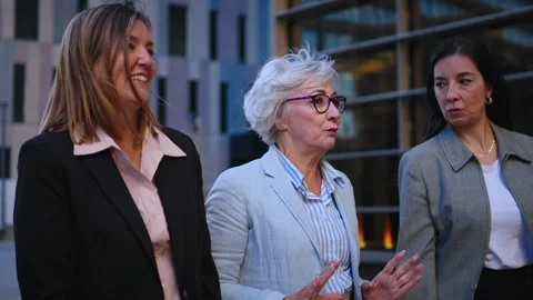 Side view three mature relaxed business women communicating walking outdoors Stock Footage 276296389