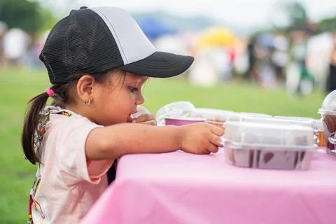 Side view of three-year-old Colombian girl interacting with pastries at chi.. Foto stock