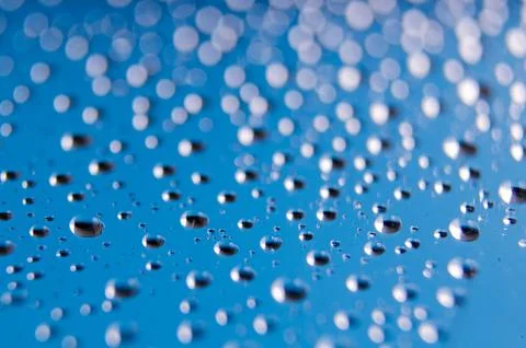 Side view of tiny water droplets on a clear blue background. Rain patterns .. Stock Photos