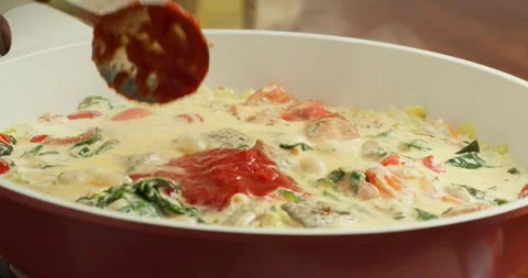 Side view: Tomatoes simmer with spinach leaves and green onions in cream in a Stock Footage 317405233