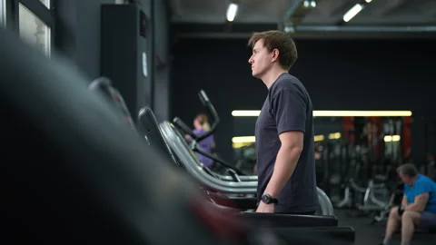 Side view tracking shot of male beginner in outfit walking on treadmill, working Video stock 273611665