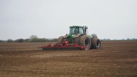 Side view of a tractor leaving, a farmer plowing a field, cultivating fertile Video stock 261933483