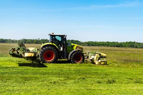 Side view of tractor with mower cutting grass on summer field Stock Photos