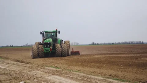 Side view of a tractor turning around, farmer plowing field, cultivating fertile Stock Footage 261933502