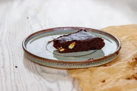 Side view of a triangular slice of homemade chocolate almond brownie served.. Stock Photos