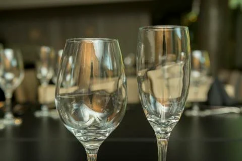 Side view of two different empty glass cups on a black table. Stock Photos