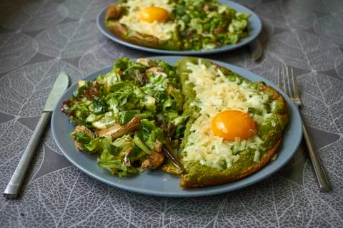 Side view of two plates with omelet and salad on the table, female hands are  Foto stock
