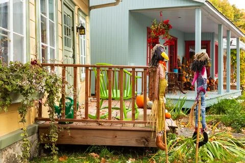 Side view of two scarecrows in front of yellow house Stock Photos