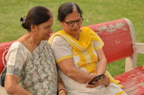 Side view of two Senior Indian woman working on mobile phone/tablet Stock Photos