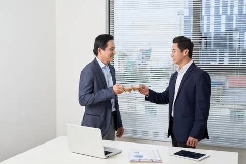 Side view of two serious young businessmen wearing black and blue suits drink Stock Photos