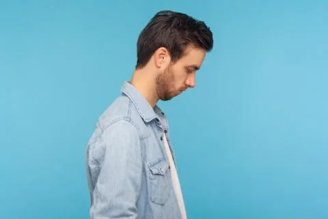 Side view of unhappy man in worker denim shirt looking down, bowing head with Foto stock