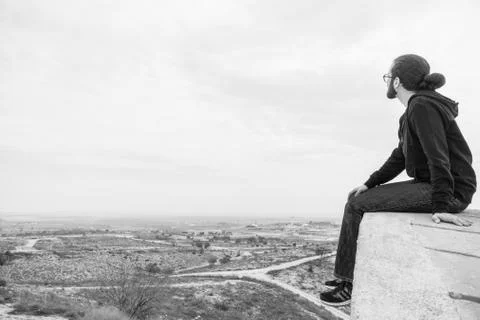 Side view unidentified young man in casual clothes and glasses sits on the hi Stock Photos