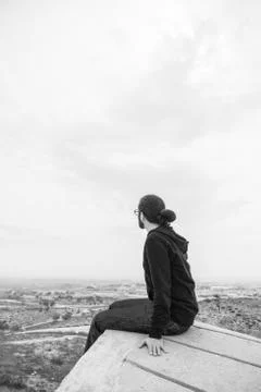 Side view unidentified young man in casual clothes and glasses sits on the hi Stock Photos