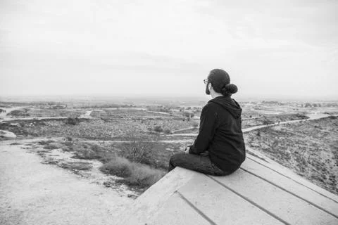 Side view unidentified young man in casual clothes and glasses sits on the hi Stock Photos