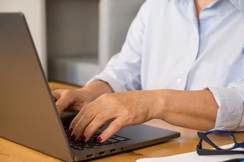 Side view on unrecognizable elder woman working on laptop Stock Photos