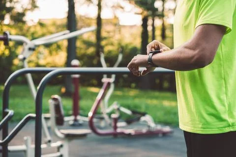 Side view, unrecognizable man in green shirt changing settings on his sports Stock Photos