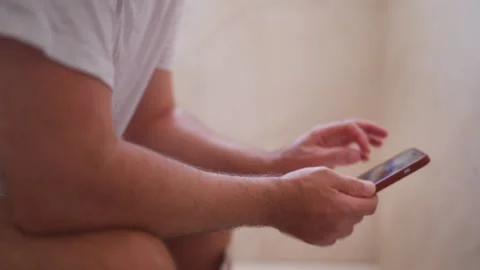 Side view of an unrecognizable man sitting on the toilet with his pants dow.. Stock Footage 342760758