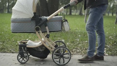 Side view of unrecognizable young Caucasian man pushing baby stroller in summer Vídeo Stock 146069862