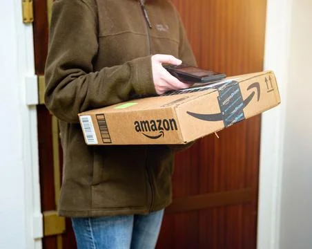 Side view of UPS female worker scanning parcel from Amazon Prime delivery before Stock Photos