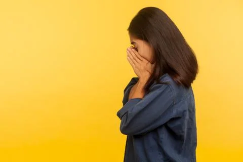 Side view of upset dramatic girl in denim shirt crying with sorrow, wiping te Stock Photos