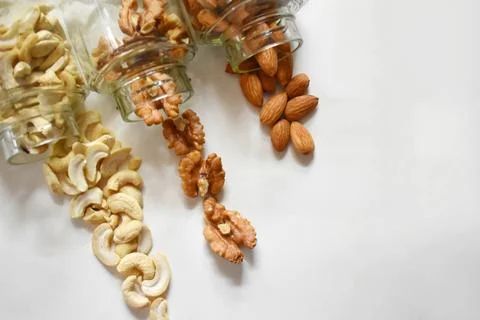 Side view of various dried fruit slices scattered from glass jars on black ba Foto stock