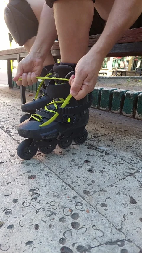 Side View Vertical 4K Close Up of Man Tying Laces on Left Inline Skate Stock Footage 346075979