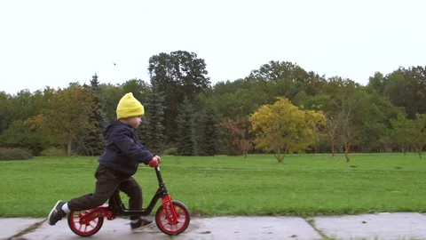 Side view video of a caucasian boy riding a bike without pedals in a green park Stock Footage 146802759