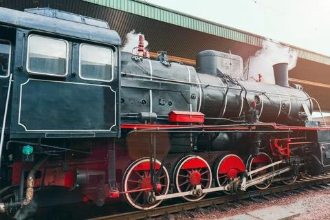Side view of a vintage steam train with red wheels and smoke Stock Photos