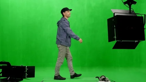 Side view of a walking man in black peaked cap on chroma key background Stock Footage