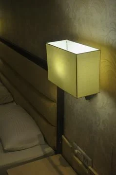 Side view of wall light lamp near to bed   Stock Photos