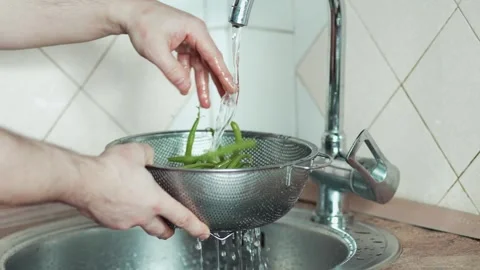 Side view of washing French beans in a stainless steel strainer at home Stock Footage 343555592