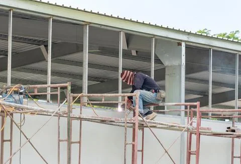 Side view of welder is welding the window. Stock Photos
