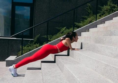 Side view of well built young woman pushing up from stairs. Athletic woman with Stock Photos