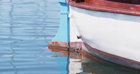 Side view of a white boat with blue trim, reflected in the calm water. Video stock 262395491
