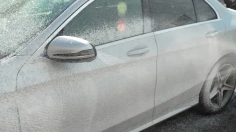 A side view of a white car covered in washing foam. Stock Footage 341331778