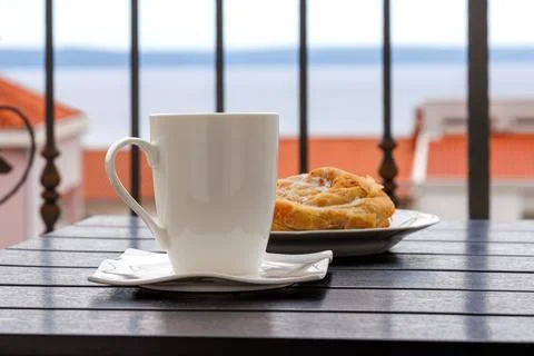 Side view of a white cup of tea and  plate with burek pastry on a balcony t.. Stock Photos