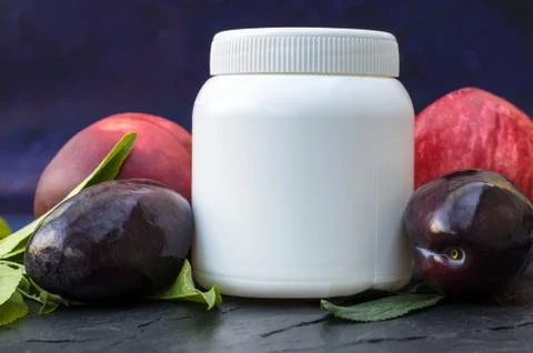 Side view of white jar with place for your text. Peaches and plums on a blue  Stock Photos