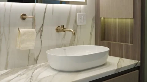 Side view of white sink with gold faucet in designer and well-lighted bathroom Video stock 249982584