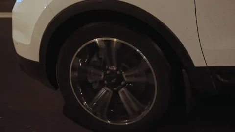 Side view of white SUV car front wheel spinning and riding on wet asphalt road Stock Footage 196545439