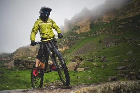 Side view wide angle partly a man on a mountain bike travels on rocky terrain Stock Photos